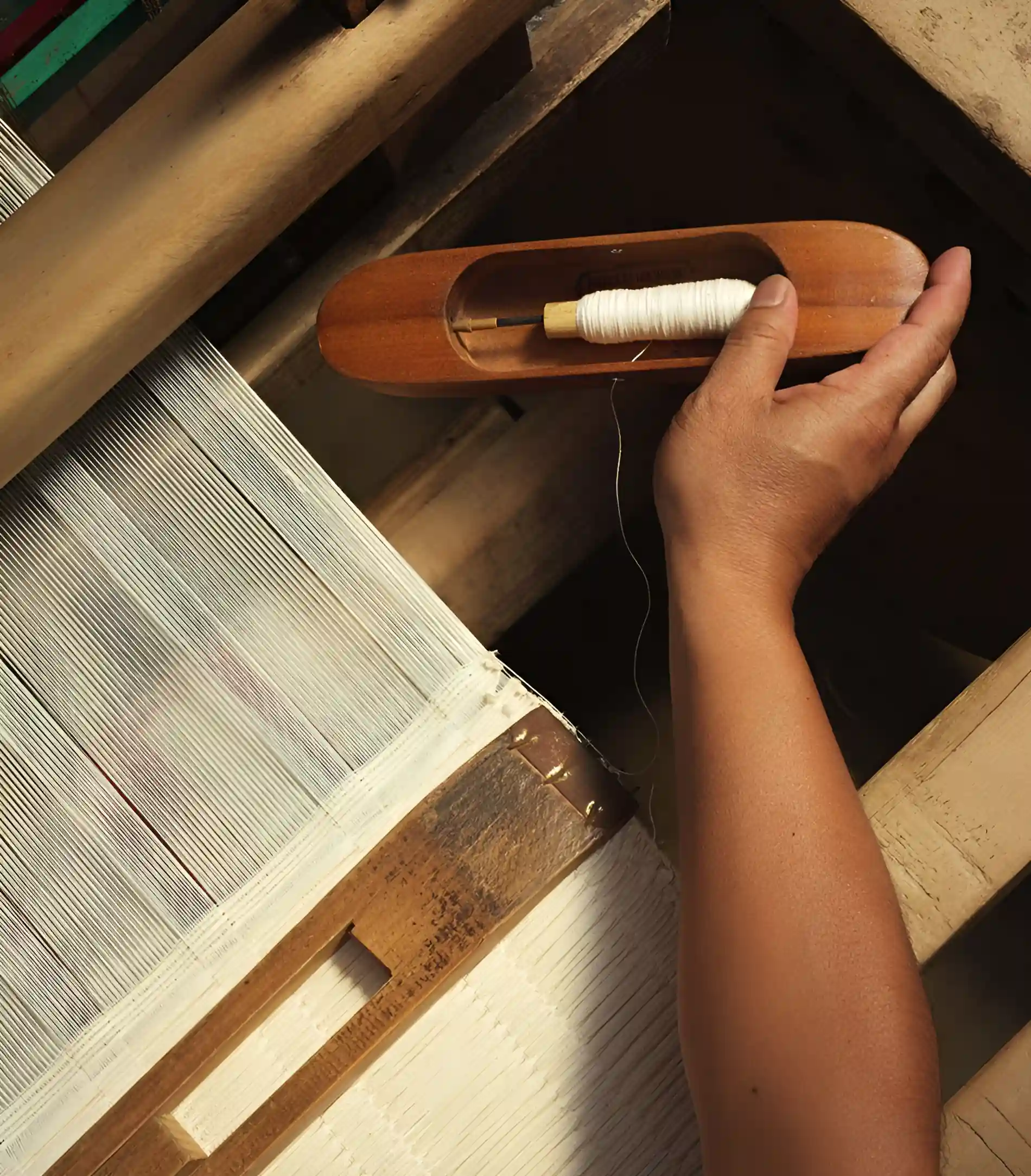 Weaving Shuttle & Warp Threads (Wooden shuttle holding spooled yarn across traditional handloom framework)